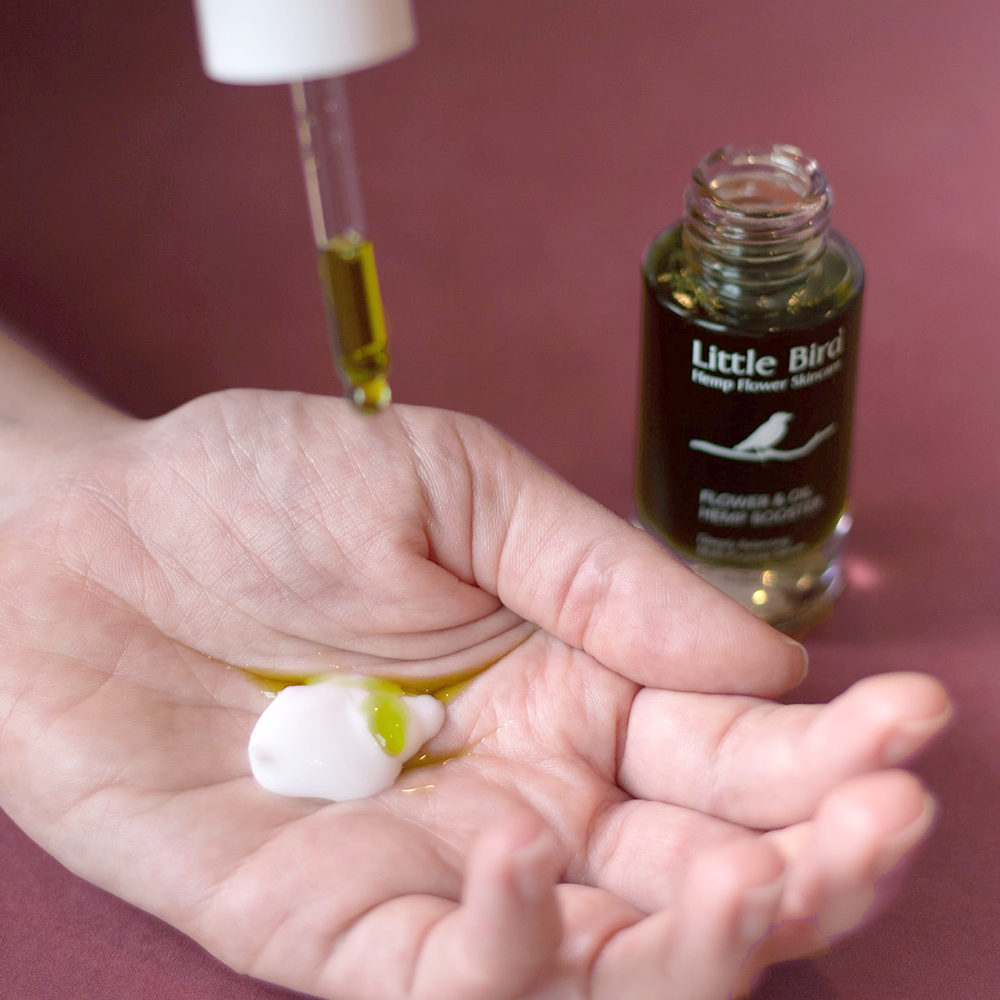 Flower and Oil Hemp Booster serum dripping into a open palm
