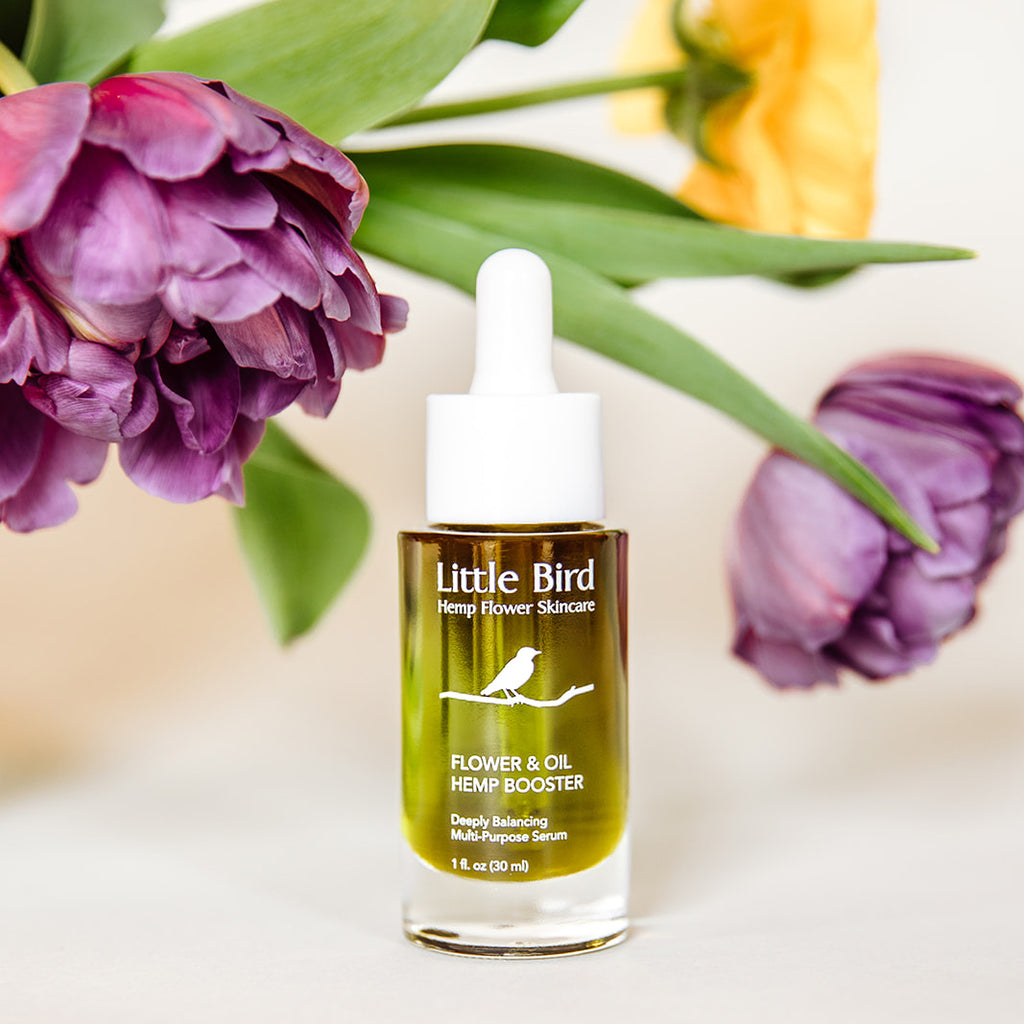 Flower and Oil Hemp Booster serum in front of colorful spring flowers